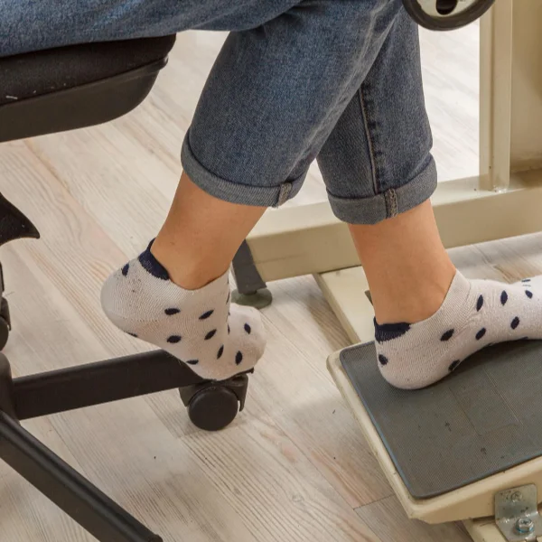 Une personne assise sur une chaise avec les pieds posés sur une machine.
