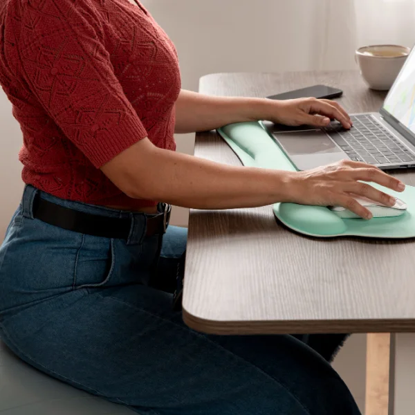 Une femme assise à un bureau, concentrée sur son travail avec des documents et un ordinateur portable devant elle.