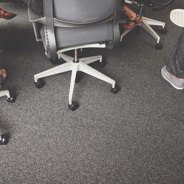 Personnes assises sur des chaises dans un bureau, illustrant l'importance du confort au travail avec un tapis ergonomique.