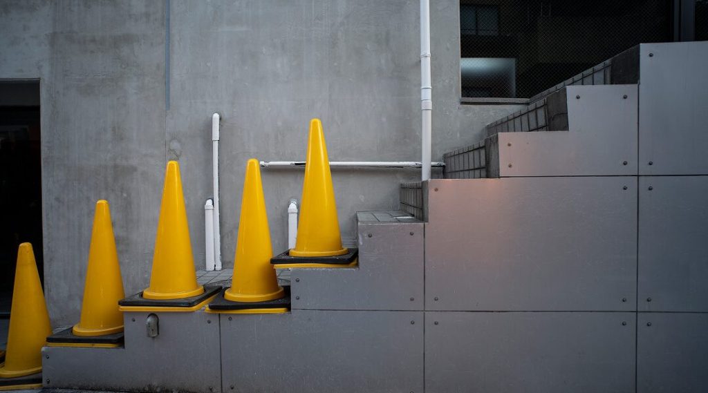 Un ensemble de cônes jaunes placés sur un escalier pour signaliser une zone de sécurité dans un environnement industriel.